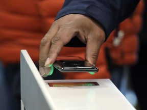 FILE- In this Jan. 22, 2018, file photo a shopper scans an Amazon Go app on a cellphone while entering an Amazon Go store in Seattle. Microsoft is working on automated checkout technology that could help retailers compete with Amazon's new cashier-less stores. One firm building automated checkout systems, AVA Retail, said Thursday, June 14 that it is working with Microsoft on the technology for physical stores.