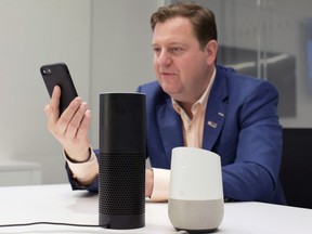 In this June 14, 2018, photo, Gareth Gaston, Executive Vice President and Head of Omnichannel Banking at US Bank, discusses voice assistant banking with a mobile phone, an Amazon Echo, center, and a Google Home, right, in New York. Big banks and financial companies have started to offer banking through virtual assistants, Amazon's Alexa, Apple's Siri, and Google's Assistant, in a way that will allow customers to check their balances, pay bills and, in the near future, send money just with their voice. Regional banking giant U.S. Bank is the first bank to be on all three services, Alexa, Siri and Assistant.