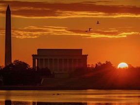 FILE - In this Tuesday, March 6, 2018, file photo, the sun peaks over the horizon next to the Washington Monument and Lincoln Memorial at daybreak along the Potomac River in Washington. Washington's primary is on Tuesday, June 19.