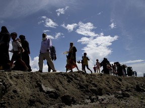 FILE - In this Oct. 2, 2017, file photo, newly arrived Rohingya Muslims from Myanmar walk as they continue their journey into a camp for refugees in Teknaf, Bangladesh. Japanese beer company Kirin is investigating whether its donations went to Myanmar's military, accused of brutal attacks against Rohingya Muslims. Amnesty International urged Japanese authorities to look into donations Kirin's subsidiary Myanmar Brewery made in September and October 2017.