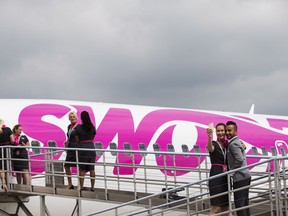 Swoop Airline employees pose for photos next to a Boeing 737 during a media event ahead of their first day of service, Tuesday, June 19, 2018 at John C. Munro International Airport in Hamilton, Ont.
