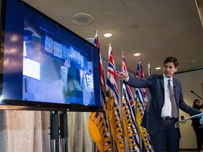 B.C. Attorney General David Eby gestures while showing a video of bundles of cash brought to a casino by a person, after releasing an independent review of anti-money laundering practices during a news conference in Vancouver, on Wednesday June 27, 2018.