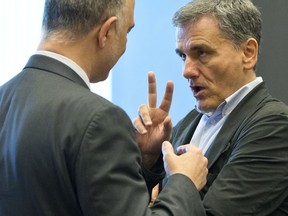 Greek Finance Minister Euclid Tsakalotos, right, speaks with European Commissioner for Economic and Financial Affairs Pierre Moscovici during a meeting of eurogroup finance ministers at EU headquarters in Luxembourg on Thursday, June 21, 2018. Eurozone nations are working on the final elements of a plan to get Greece successfully out of its eight-year bailout program and keep its massive debt burden manageable.