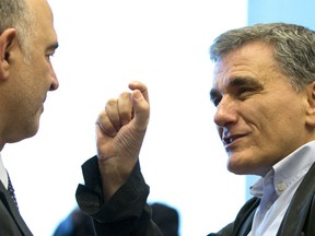 Greek Finance Minister Euclid Tsakalotos, right, speaks with European Commissioner for Economic and Financial Affairs Pierre Moscovici during a meeting of eurogroup finance ministers at EU headquarters in Luxembourg on Thursday, June 21, 2018. Eurozone nations are working on the final elements of a plan to get Greece successfully out of its eight-year bailout program and keep its massive debt burden manageable.