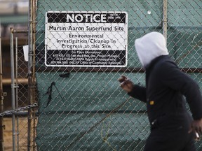 FILE - In this Dec. 11, 2017, file photo, a man walks past a notice for the Martin Aaron Inc. Superfund site in Camden, N.J. A lawyer tapped to lead a task force at the Environmental Protection Agency overseeing cleanups at the nation's most polluted places until recently worked for a top chemical and plastics manufacturer with a troubled legacy of creating some of those toxic sites.