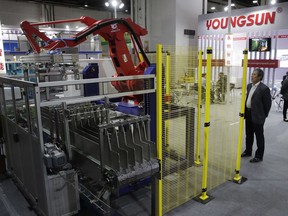 In this April 12, 2018, photo, a visitor watches a Chinese company displaying a Chinese-made industrial robot demonstration on processing soybean at the International soybean exhibition in Shanghai. China says it will narrow its trade surplus with the United States but rejects pressure to change technology development tactics seen as a path to prosperity and its rightful place as a global leader. Beijing highlighted the sensitivity of the issue with its threat to scrap deals aimed at settling a sprawling trade dispute with Washington if President Donald Trump's threatened tariff hike on $50 billion of Chinese technology goes ahead.