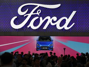FILE - In this file photo taken Wednesday, April 25, 2018, visitors and journalists crowd near a Ford Focus on display at the Ford exhibit during the media day for the China Auto Show in Beijing. China has eased limits on foreign ownership in auto manufacturing, insurance, and other fields but didn't directly address complaints that are fueling conflict with Washington over trade and technology.