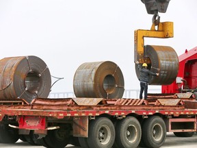 In this May 19, 2018, photo, a worker positions a roll of steel plate at a dockyard in Qidong in eastern China's Jiangsu province. China appealed Friday, June 1, 2018, to its trading partners to reject "trade and investment protectionism" after Washington raised tariffs on steel imports and said it will impose curbs on Chinese investment. (Chinatopix via AP)