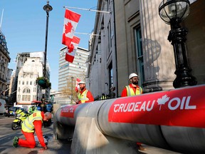 Demonstrators use a mock oil pipeline to block the entrance to the Canadian Embassy in  London this spring as they protest against the Trans Mountain oil pipeline.