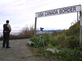 A Canadian Customs and Fisheries officer watches over the U.S.-Canada border between Blaine, Washington and White Rock, British Columbia in 2001.