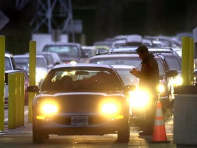 A U.S. Customs officer checks cars line up the border at Blaine, Washington.