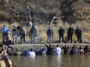 FILE - In this Nov. 2, 2016 file photo, protesters demonstrating against the expansion of the Dakota Access Pipeline wade in cold creek waters confronting local police as remnants of pepper spray waft over the crowd near Cannon Ball, N.D. North Dakota is demanding $38 million from the federal government to reimburse the state for costs associated with policing large-scale and prolonged protests against the oil pipeline. North Dakota Attorney General Wayne Stenehjem filed an administrative claim Friday, July 20, 2018.