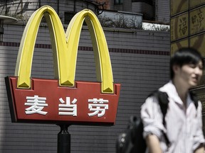 A pedestrian walks past a sign for McDonald's Corp. in Shanghai.