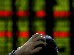 A man scratches his head as he checks the stock prices in Beijing.