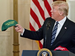 U.S. President Donald Trump holds up a "Make Our Farmers Great Again" hat while speaking during a "Made in America" products showcase in the Cross Hall of the White House in Washington, D.C., U.S., on Monday, July 23, 2018.