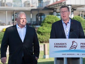 Ontario Premier Doug Ford, left, and Saskatchewan Premier Scott Moe talk with reporters as the Canadian premiers meet in St. Andrews, N.B. on Thursday.