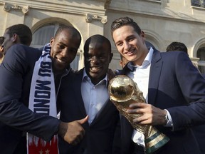 From left, France's Djibril Sidibe, N'Golo Kante and Florian Thauvin pose with the World Cup trophy during an official reception at the Elysee Presidential Palace in Paris, Monday, July 16, 2018. France is readying to welcome home the national soccer team for a parade down the Champs-Elysees, where tens of thousands thronged after the team's 4-2 victory over Croatia Sunday.