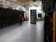 A worker walks along a row of computer rigs that run around the clock 'mining' bitcoin inside the Genesis Mining cryptocurrency mine in Keflavik, Iceland.