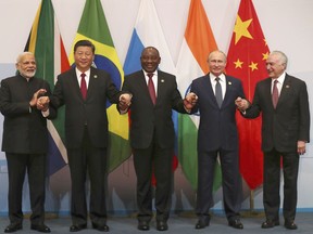 Members of the major emerging national economies group BRICS, with from left, Indian Prime Minister Narendra Modi, China's President Xi Jinping, South African President Cyril Ramaphosa, Russia's President Vladimir Putin, and Brazil's President Michel Temer, as they pose together for a group photo at the BRICS summit in Johannesburg, South Africa, Thursday, July 26, 2018. Chinese President Xi Jinping said Wednesday the world faces "a choice between cooperation and confrontation".