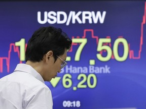 A currency trader walks by the screen showing the foreign exchange rate between U.S. dollar and South Korean won at the foreign exchange dealing room in Seoul, South Korea, Monday, July 23, 2018. Asian markets were mostly lower on Monday as concerns over trade tensions moved to the forefront at the meeting this weekend of the Group of 20 industrial nations.