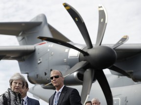 British Prime Minister Theresa May, left, speaks with Airbus CEO Tom Enders, from Germany, backdropped by an Airbus A400M Atlas military transport aircraft at the Farnborough Airshow in Farnborough, England, Monday, July 16, 2018.