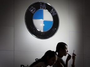 FILE - In this file photo dated Friday, Sept. 25, 2015, Models prepare to work at the BMW booth during the Imported Auto Expo in Beijing, China. Automaker BMW said Monday July 9, 2018, it will have to raise prices on the U.S.-built SUVs it sells in China due to 40 percent import tax on cars from the United States,  in retaliation for higher tariffs on Chinese goods imposed by President Donald Trump.