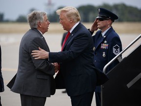 President Donald Trump is greeted by Gov. Mike Parson, R- Mo., after arriving at St. Louis Lambert International Airport, Thursday, July 26, 2018, in St. Louis, Mo.