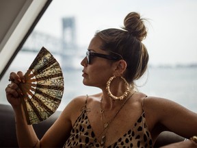 A woman fans herself to keep cool on the ferry en route to Rockaway Beach in New York, Sunday, July 1, 2018.