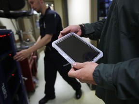 Inmate Anthony Plant holds a tablet that he checked out from corrections officer Glen Dinning, left, at the Corrections Transitional Work Center, a low risk security section at the New Hampshire State Prison for Men, in Concord, N.H., Monday, July 23, 2018. Inmates across the country are getting access to technology via tablets in an effort to help their education, keep them connected to family and reduce noise and violence in prison.
