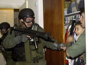 FILE - In this April 22, 200, file photo, by Associated Press photojournalist Alan Diaz, Elian Gonzalez is held in a closet by Donato Dalrymple, one of the two men who rescued the boy from the ocean, right, as government officials search the home of Lazaro Gonzalez for the young boy, in Miami.  Retired Associated Press photojournalist Alan Diaz, whose photo of the terrified 6-year-old Cuban boy named earned him the Pulitzer Prize, died Tuesday, July 3, 2018, his daughter Aillette Rodriguez-Diaz said. He was 71.