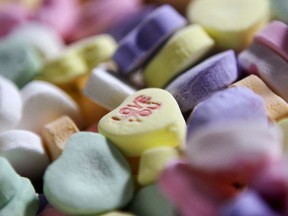 FILE - In this Jan. 14, 2009, file photo, colored "Sweethearts" candy is held in bulk prior to packaging at the New England Confectionery Company in Revere, Mass. The owner of a company that makes candies such as Necco wafers and Sweethearts has unexpectedly shut down operations at its Massachusetts plant. The Boston Globe reported Round Hill Investments LLC announced Tuesday, July 24, 2018, it is selling Necco brands to another confection manufacturer and closing down its Revere plant.