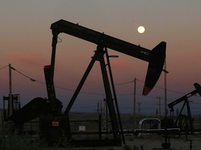 FILE - In this June 8, 2017, file photo, oil derricks are busy pumping as the moon rises near the La Paloma Generating Station in McKittrick, Calif. The U.S. is on pace to leapfrog both Saudi Arabia and Russia as the world's biggest oil producer.