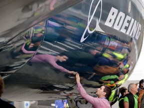 FILE- In this Feb. 5, 2018, file photo, Boeing worker Paul Covaci reaches out to touch a Boeing 737 MAX 7, the newest version of Boeing's fastest-selling airplane, during a debut for employees and media of the new jet in Renton, Wash. Boeing Co. says its second-quarter profit was $2.2 billion. The Chicago-based company said Wednesday, July 25, it had profit of $3.73 per share on revenue of $24.26 billion. Earnings, adjusted for non-recurring gains, were $3.33 per share.
