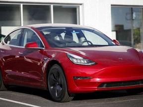 FILE- In this May 27, 2018, file photo, a 2018 Model 3 sedan sits at a Tesla dealership in Littleton, Colo. Tesla Inc. made 5,031 lower-priced Model 3 electric cars during the last week of June, surpassing its often-missed goal of 5,000 per week. Tesla reported making 28,578 Model 3s from April through June, according to its quarterly production release on Monday, July 2.
