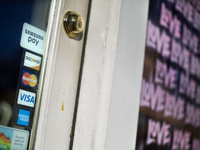 FILE- In this Jan. 31, 2018, file photo, credit card logos are posted to the door of a business in Atlanta. On Monday, July 9, the Federal Reserve releases its May report on consumer borrowing.
