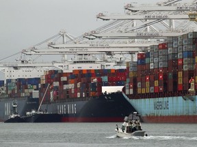 In this July 2, 2018, photo container ships are unloaded at the Port of Oakland in Oakland, Calif. On Friday, July 6, the Commerce Department reports on the U.S. trade gap for May.