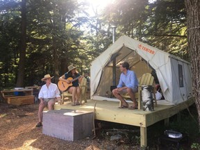 In this Friday, June 29, 2018, photo, Michael D'Agostino, right, sits with Robert and Sally McCracken at their Tentrr campsite in Sand Lake, N.Y. D'Agostino, CEO of Tentrr, says it's like Airbnb or Uber for the great outdoors, providing a platform for landowners to earn some cash by sharing secluded and scenic sites for camping.
