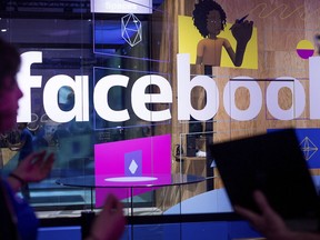 FILE - In this Tuesday, April 18, 2017, file photo, conference workers speak in front of a demo booth at Facebook's annual F8 developer conference, in San Jose, Calif. The chairman of the U.K. Parliament's media committee says the government office that investigated the Cambridge Analytica scandal has fined Facebook 500,000 pounds ($663,000) for failing to safeguard users' data.