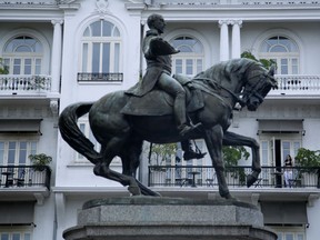 In this May 22, 2018 photo, a tourist overlooks Plaza Herrera, featuring a statue of General Tomas Herrera, from her balcony at the American Trade luxury hotel in the Casco Viejo neighborhood of Panama City. Ariana Lyma Young, director of the governmental Historic Heritage agency that approves building restoration projects, acknowledged the real estate boom has affected poor residents but said the economic benefits have been tremendous.