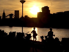 People gather along the river Main as the sun sets in Frankfurt, Germany, Saturday, July 7, 2018.