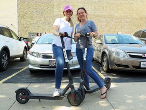 In this Wednesday, July11, 2018 photo, Kirby Bridges, left, and Megan Garlington pose with the Bird scooters they were taking for an afternoon ride in Milwaukee. Milwaukee is suing California-based Bird to stop the company from renting bikes because the city contends they are illegal to operate on streets and sidewalks.