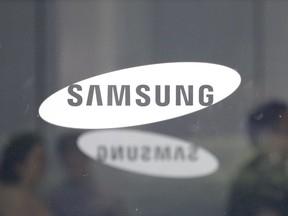 Employees walk past logos of the Samsung Electronics Co. at its office in Seoul, South Korea, Tuesday, July 31, 2018. Samsung Electronics Co. said Tuesday its second-quarter earnings rose 2 percent over a year earlier, missing expectations due to sales of smartphones and display panels that offset robust memory chip sales.