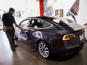 An employee cleans a Tesla Inc. Model 3 electric vehicle on display at the company's showroom in Newport Beach, California. One of the Model 3's biggest critics has reversed course and says the sedan is profitable.