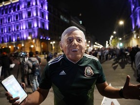 A supporter of presidential candidate Andres Manuel Lopez Obrador wearing a mask in the likeness of the candidate, celebrates his victory, in Mexico City's main square, the Zocalo, Sunday, July 1, 2018. Official quick count in Mexico presidential election says leftist Lopez Obrador won over 50 percent of votes.