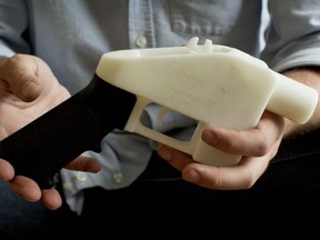 FILE - In this May 10, 2013, file photo, Cody Wilson holds what he calls a Liberator pistol that was completely made on a 3-D-printer at his home in Austin, Texas. Eight states filed suit Monday, July 30, 2018, against the Trump administration over its decision to allow a Texas company to publish downloadable blueprints for a 3D-printed gun, contending the hard-to-trace plastic weapons are a boon to terrorists and criminals and threaten public safety.