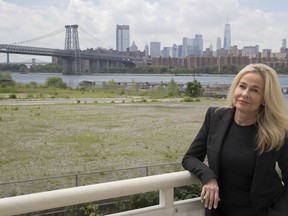 In this June 28, 2018 photo, Sabine Anton poses for a photo on the balcony of her apartment in the building overlooking lower Manhattan and the Williamsburg bridge at 184 Kent Avenue in the Brooklyn borough of New York. An Associated Press investigation into one of the Kushner Cos.' largest residential buildings in New York City reveals what some residents say was a campaign that used noisy construction to push rent-stabilized tenants out and bring high-paying condo buyers in. More than a dozen tenants told the AP that they were subjected to relentless banging, drilling, dust and rats.