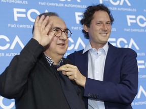 FILE - In this June 1, 2018, file photo, John Elkann, president of the FCA Italy group, right, holds a necktie to Fiat Chrysler CEO Sergio Marchionne prior to a press conference at the FCA headquarter, in Balocco, Italy. Giuseppe Berta, an industrial historian who has written books about Fiat and Fiat Chrysler and who personally knew Marchionne, expressed surprise that heir to the Fiat-founding Agnelli family, FCA Chairman John Elkann, had remained unaware of Marchionne's illness.