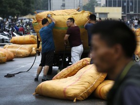 Vendors load their goods outside a retail and wholesale clothing mall in Beijing, Monday, July 16, 2018. China's economic growth slowed in the quarter ending in June, adding to challenges for Beijing amid a mounting tariff battle with Washington.