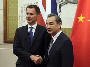 Britain's Foreign Minister Jeremy Hunt, left, shakes hands with his Chinese counterpart Wang Yi as they pose for a photograph before their meeting at the Diaoyutai State Guesthouse in Beijing, Monday, July 30, 2018.