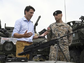 Canadian Prime Minister Justin Trudeau, left, speaks to a Latvian soldier as he inspects the troops as he visits Adazi Military Base in Kadaga, Latvia, on Tuesday, July 10, 2018. Canadian prime minister says he hopes the upcoming NATO summit will send a message of broad support for unity and solidarity but acknowledges that there will "no doubt be calls for greater investments in defense spending" - a key issue that is badly dividing the military alliance.